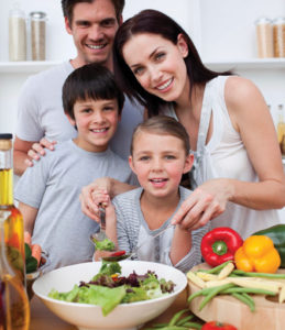 Young  mother cooking vegetables in kitchen with her family